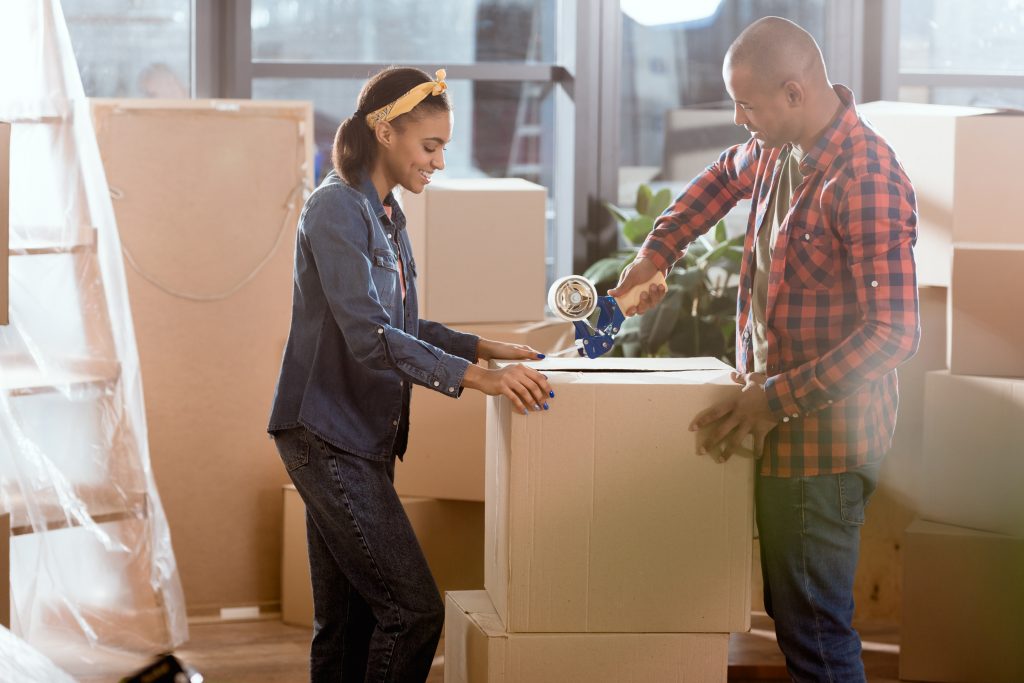 Couple moving box into new apartment