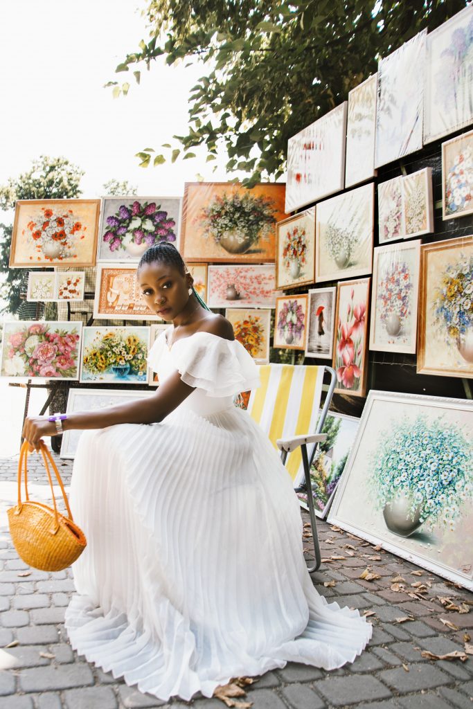 Woman posing solo in front of photo display at market.